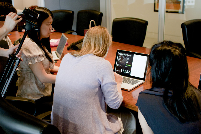 Photo of user testing session: participant at a computer with a researcher on either side while being videotaped