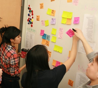 Project group discussing notes at the whiteboard